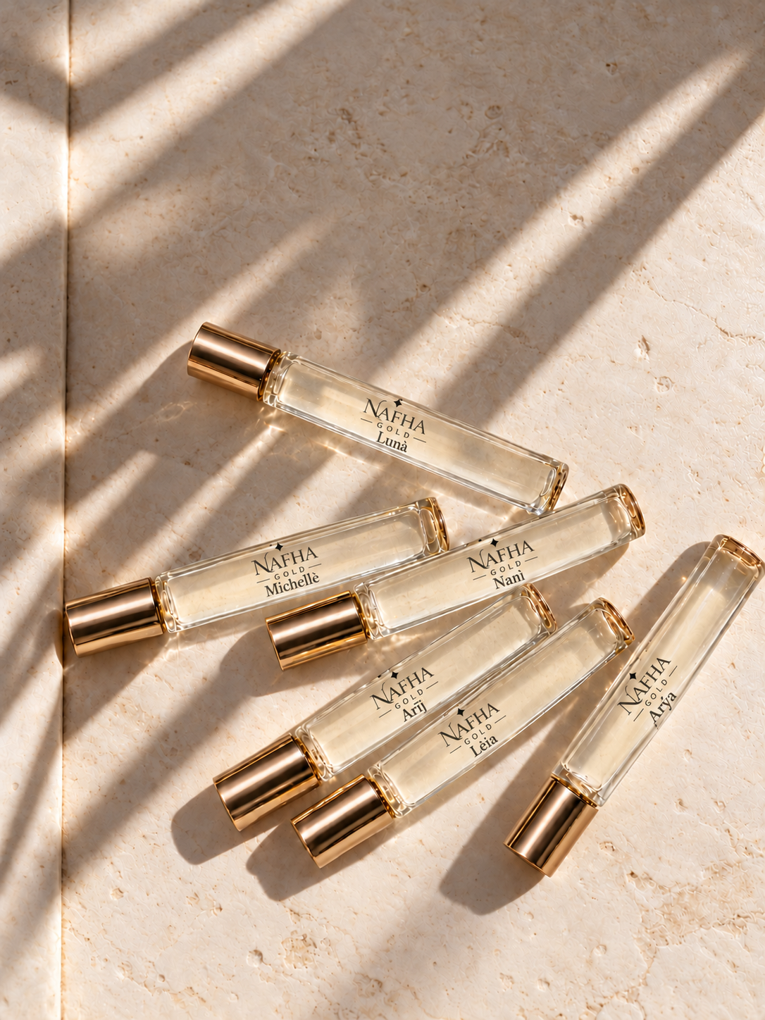 Six Nafha Gold roll-on perfumes with gold covers and pale champagne liquid in warm sunlight