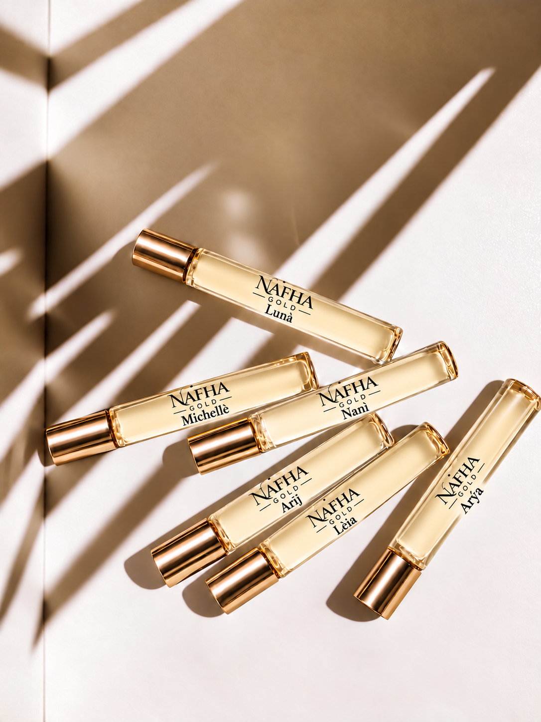 Six Nafha Gold roll-on perfumes with gold covers and pale champagne liquid in warm sunlight