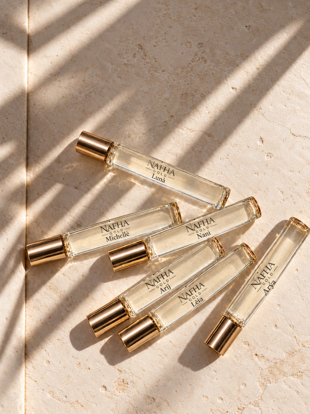 Six Nafha Gold roll-on perfumes with gold covers and pale champagne liquid in warm sunlight